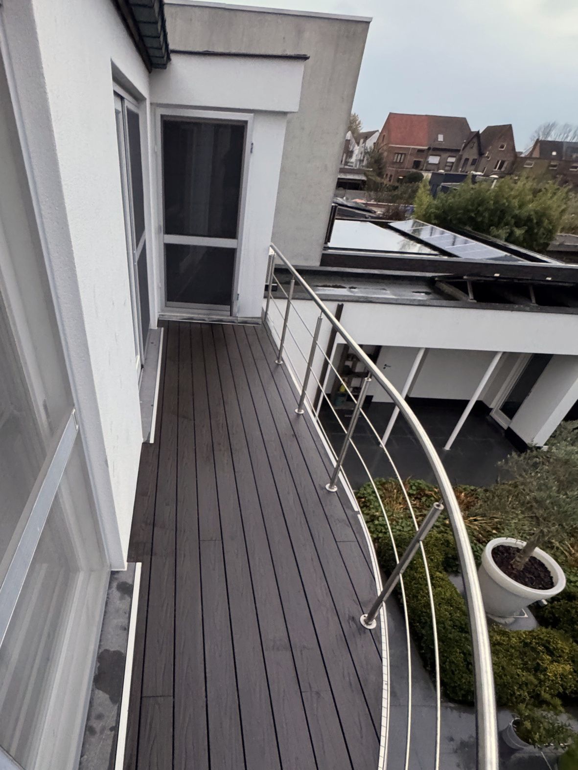 Dakterras in EvoWood-planken in de kleur taupe, met een gebogen reling in inox langs de dakrand
