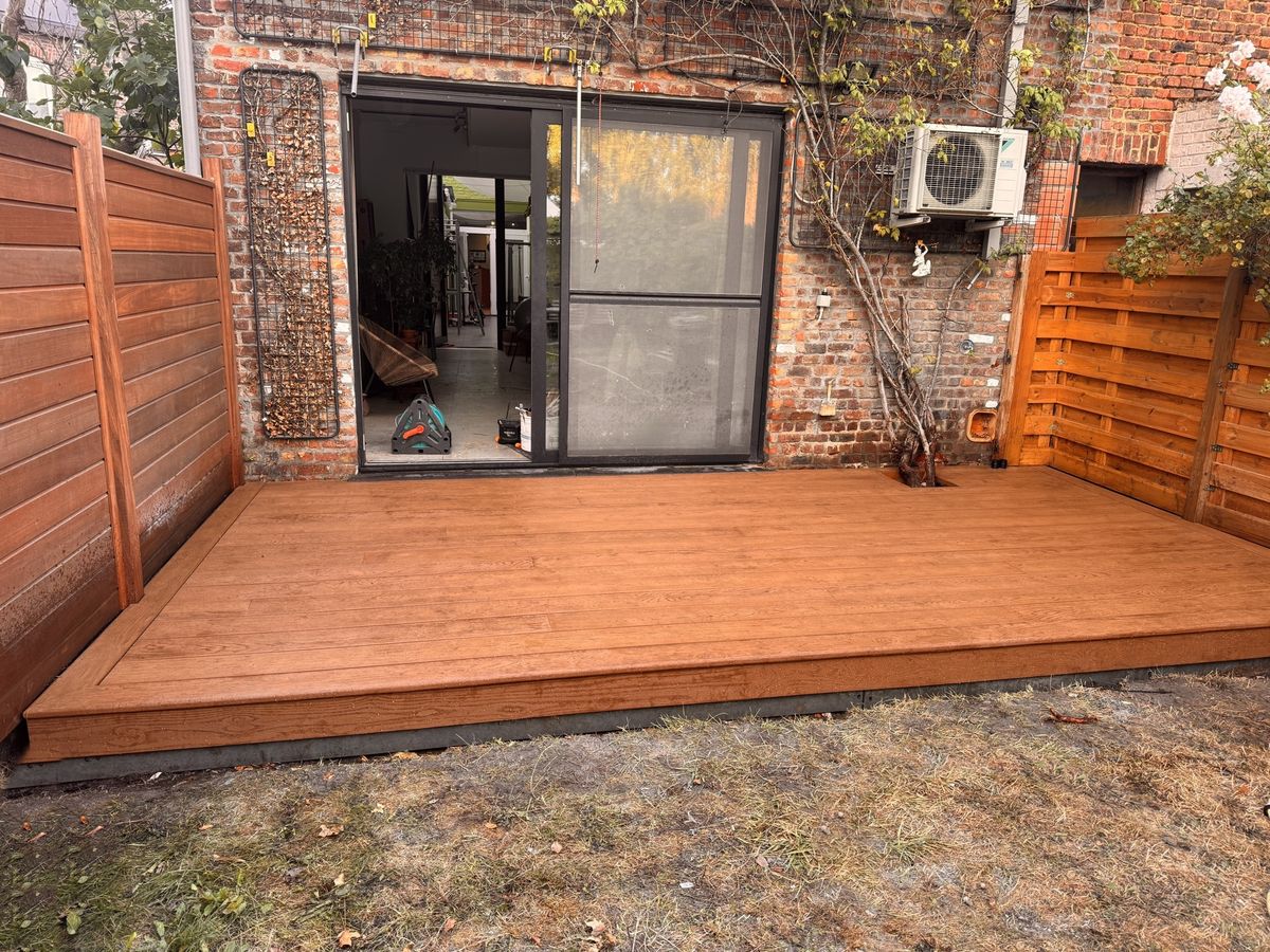 Het afgewerkte Millboard-terras voor het schuifraam, over de volle breedte van de tuin