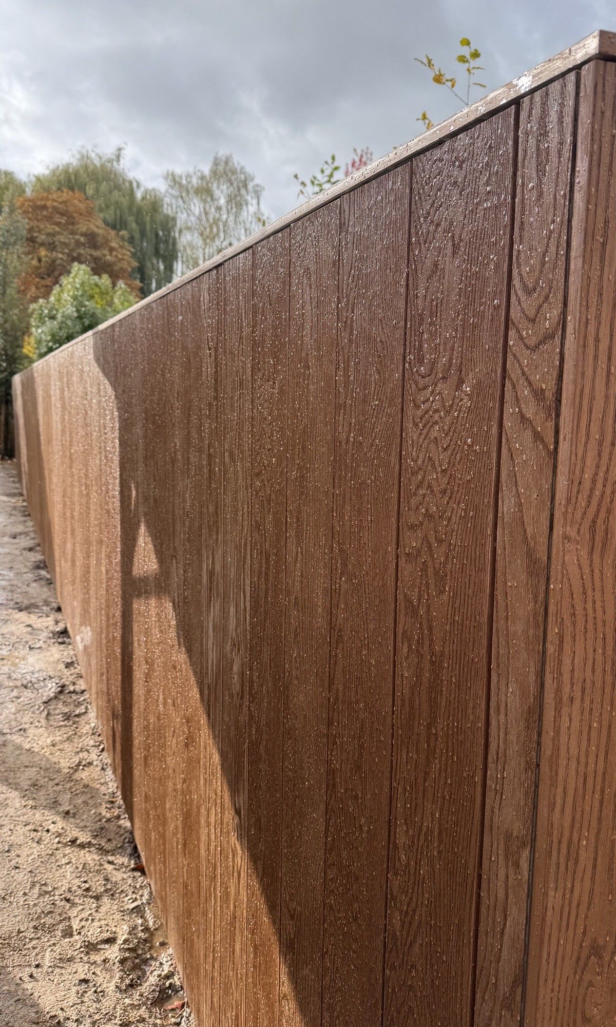 Detail van de Millboard-planken van de tuinwand, met houtnerf en afdeklijst